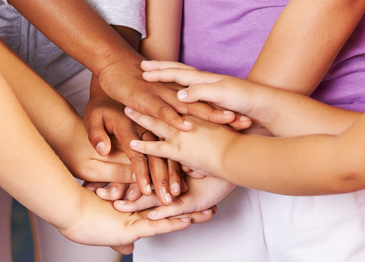 Many children stacking hands as symbol for teamwork and motivation